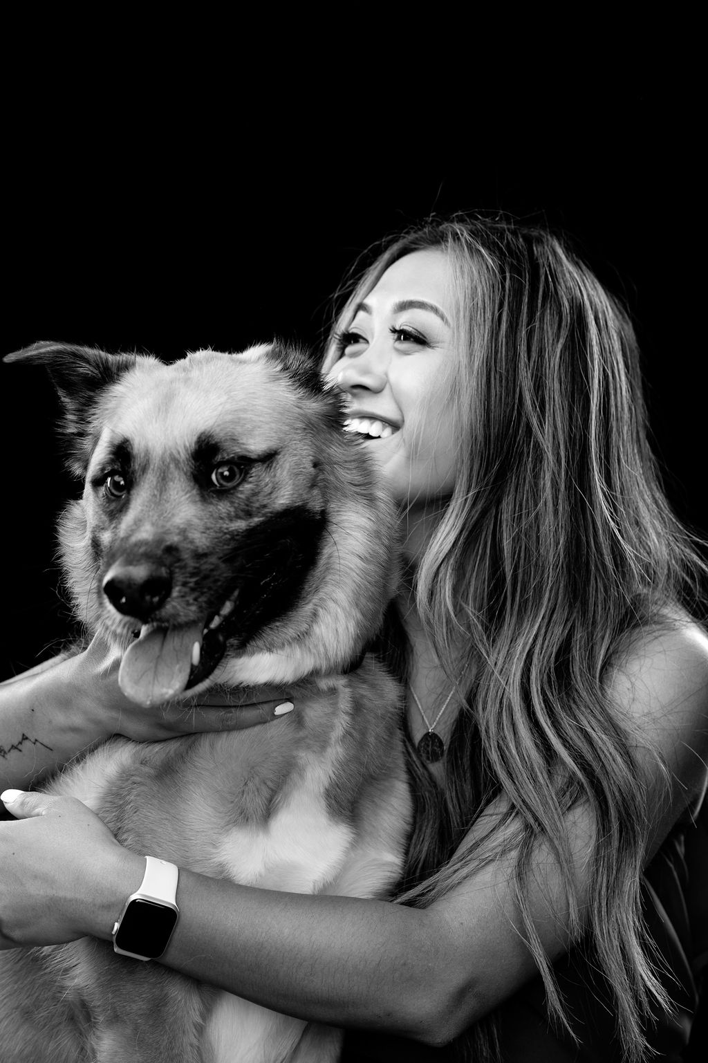 studio photoshoot with dog Joey and his mom. The picture is black and white and both are looking to the side smiling
